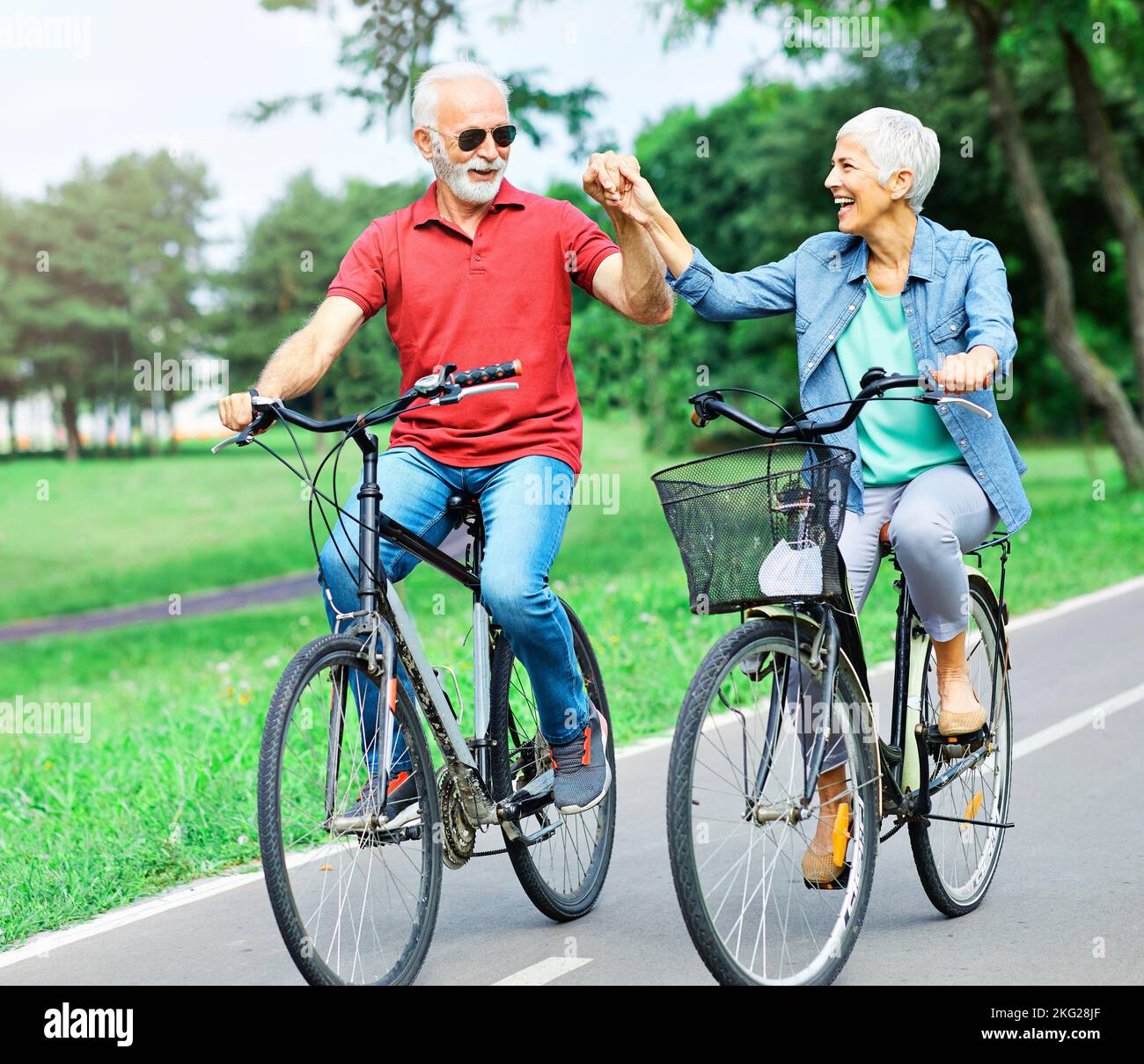 senior couple happy elderly love together retirement bicycle bike man woman mature fun Stock Photo