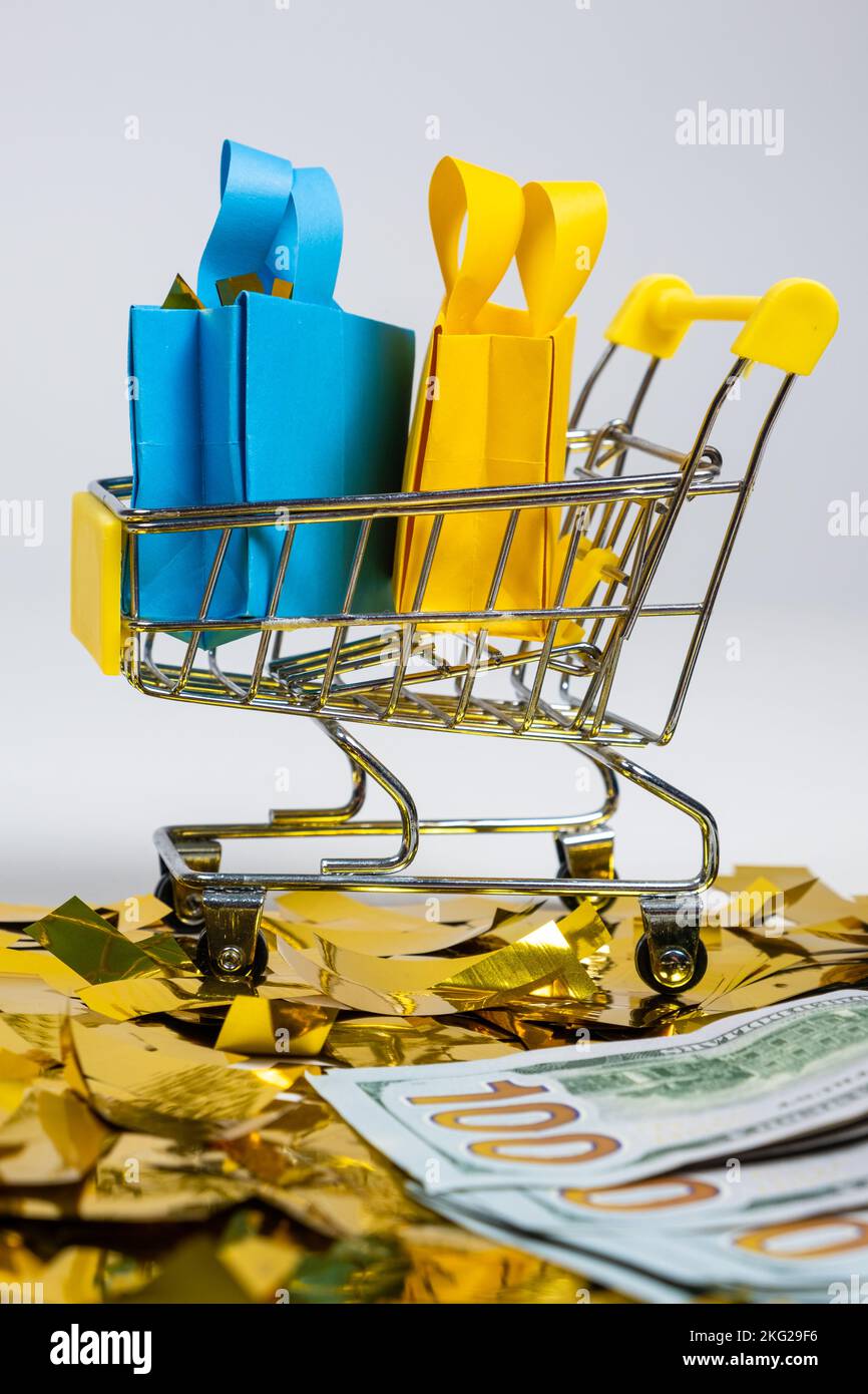 Shopping bags in a cart and money on sequins on a white background. The concept of sale. Stock Photo