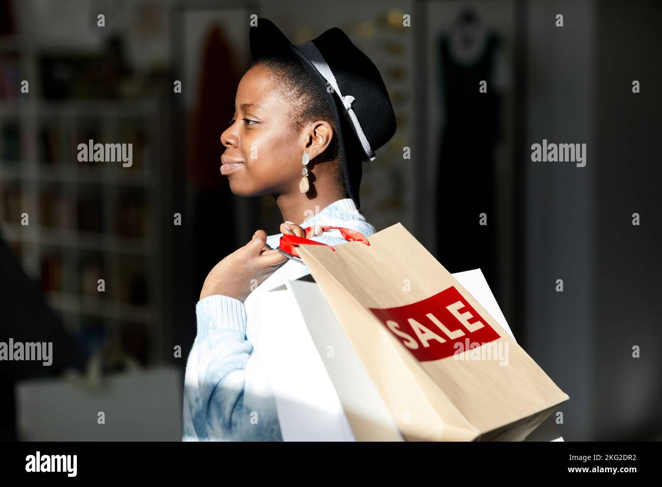 Side view portrait of smiling black woman holding shopping bags in ...