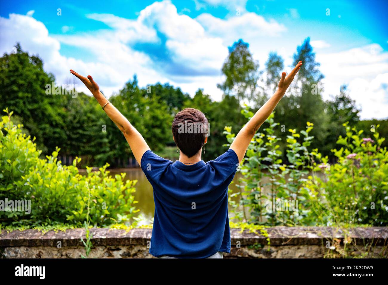 Woman raising arms in a garden in western France Stock Photo