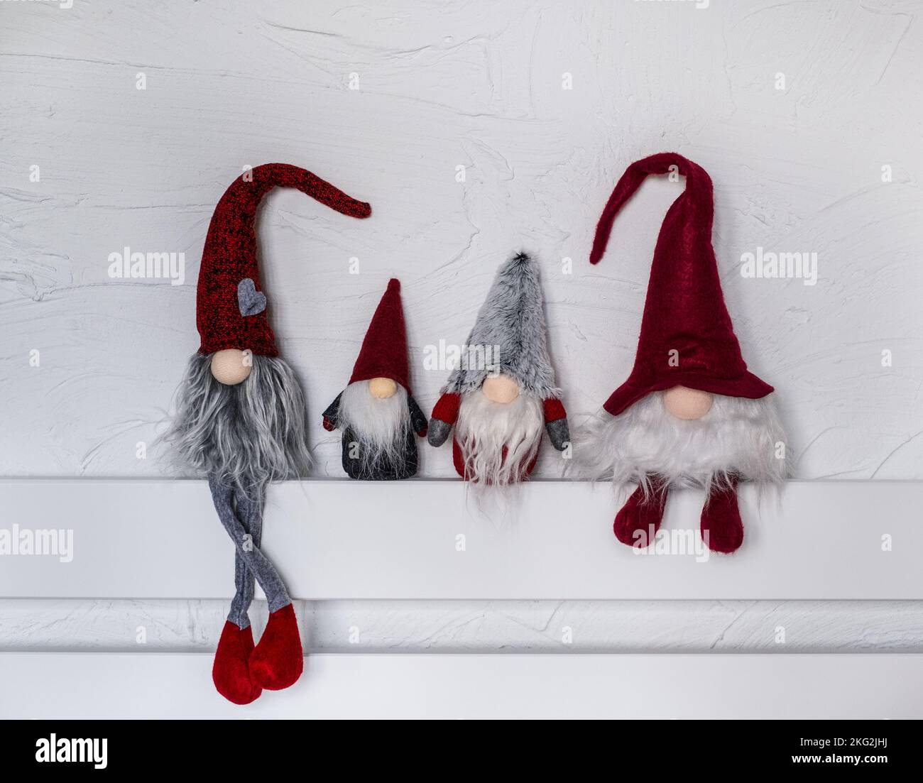 Elf Christmas decorations. Four gnomes in a red hats sit on a wooden