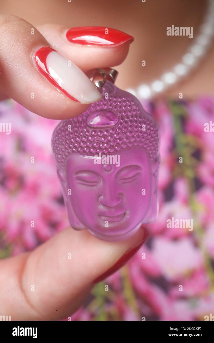 Pink Buddha head pendant in hand. Buddhist symbol Stock Photo Alamy