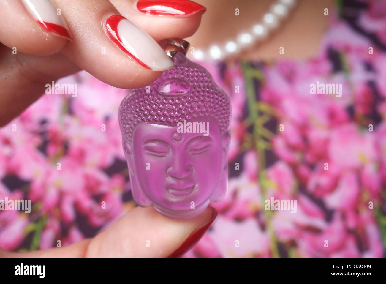 Pink Buddha head pendant in hand. Buddhist symbol Stock Photo Alamy