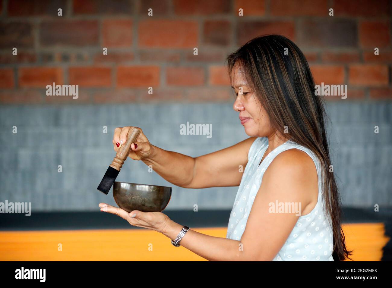 Woman using a tibetan singing bowl.  Self care, meditation, recreation, yoga and sound therapy.  Vietnam. Stock Photo