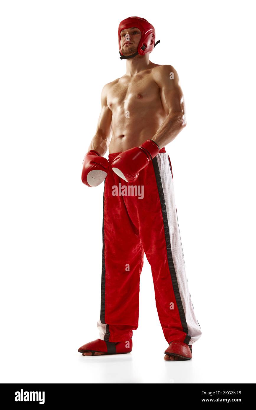 Strong and muscled male kickboxer in red sportswear and boxing gloves