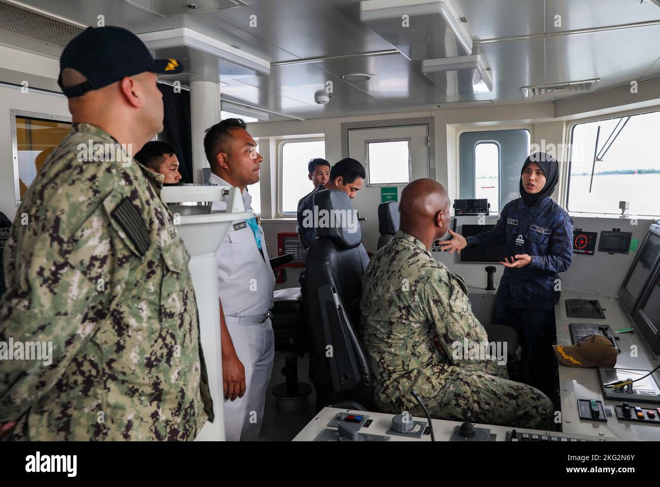 221025-N-FO714-1171  MUARA, Brunei (Oct. 25, 2022) Royal Brunei Navy Lt. j.g. Hayat Nabilah, acting navigation officer of Darussalam-class offshore patrol vessel KDB Daruttaqwa (DTQ 09), gives a tour of the ship’s pilot house to Capt. Walter Mainor, commander, Task Force 71, and Cmdr. Clayton Beas, commanding officer of Independence-class littoral combat ship USS Charleston (LCS 18) during Cooperation Afloat Readiness and Training (CARAT) Brunei, Oct. 25. CARAT Brunei 2022 highlights the 28th anniversary of CARAT among Allies and partners as a way to demonstrate long-term commitment to strengt Stock Photo