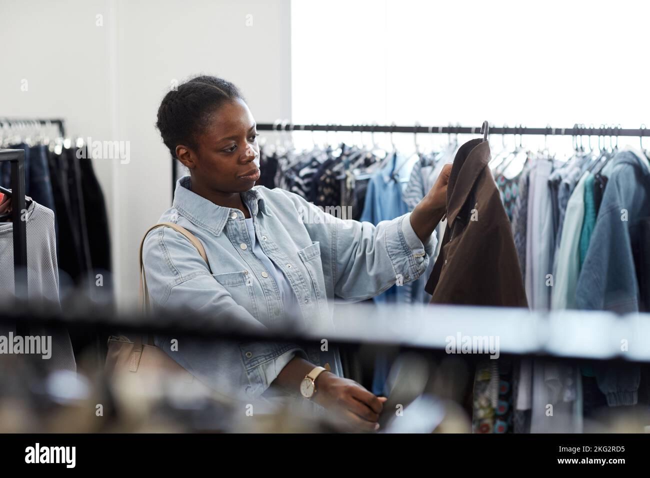 Waist up portrait of black young woman looking at clothes in thrift store Stock Photo