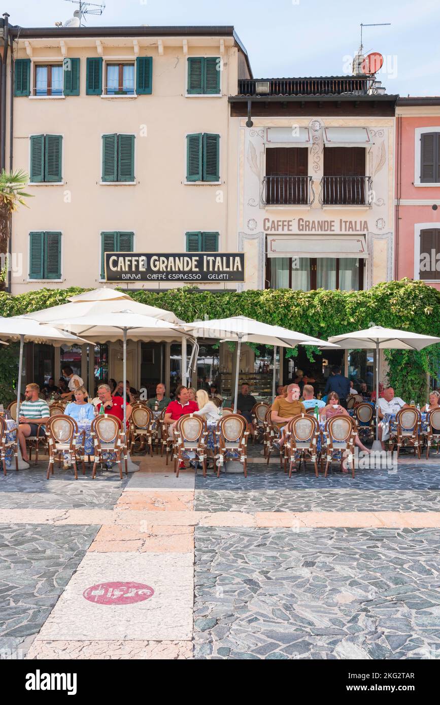 Europe cafe bar, view in summer of people sitting at cafe tables in the Piazza Carducci in the Lake Garda resort town of Sirmione, Lombardy, Italy Stock Photo