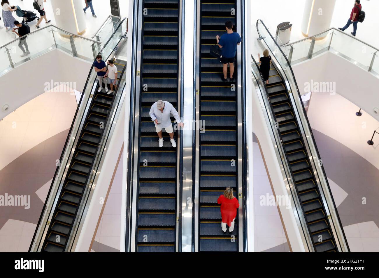 Shopping center, Dubai Mall. Shoppers riding escalator. United Arab