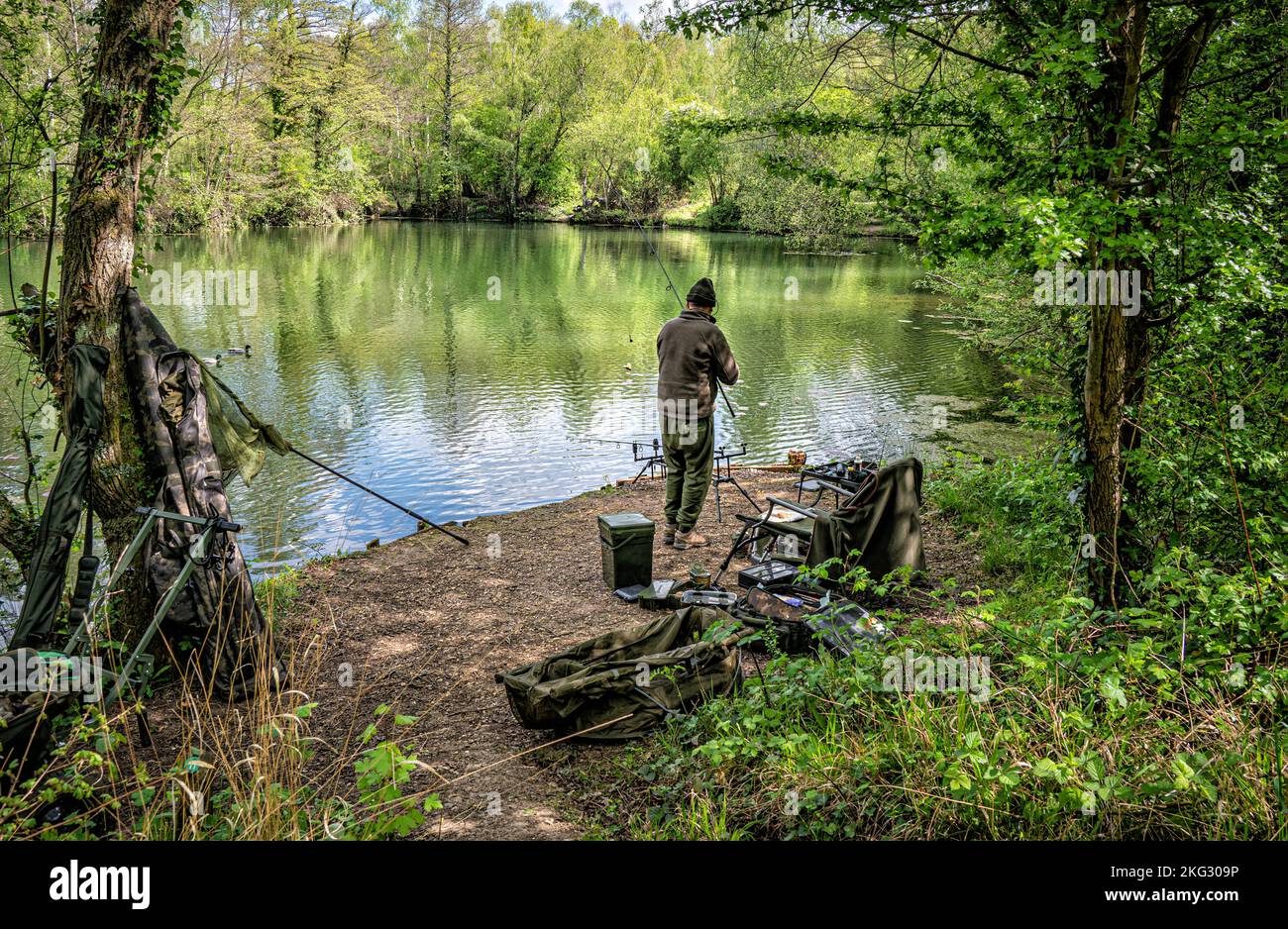 Back view of fisherman by the lake side at Swanick Lakes nature reserve an old cement quarry. Stock Photo