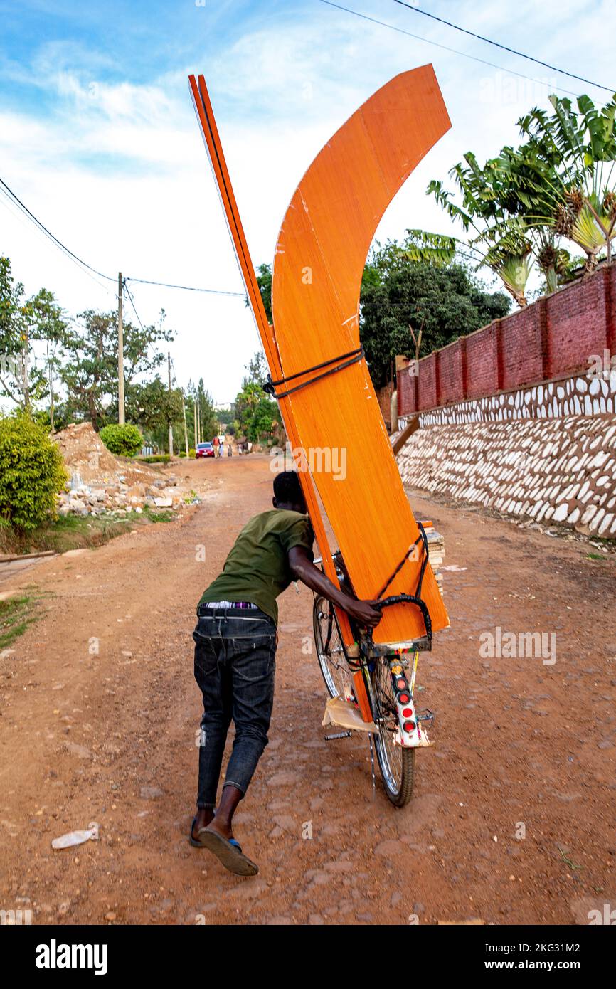 Young man pushing a bike with a heavy load in Kigali, Rwanda Stock Photo