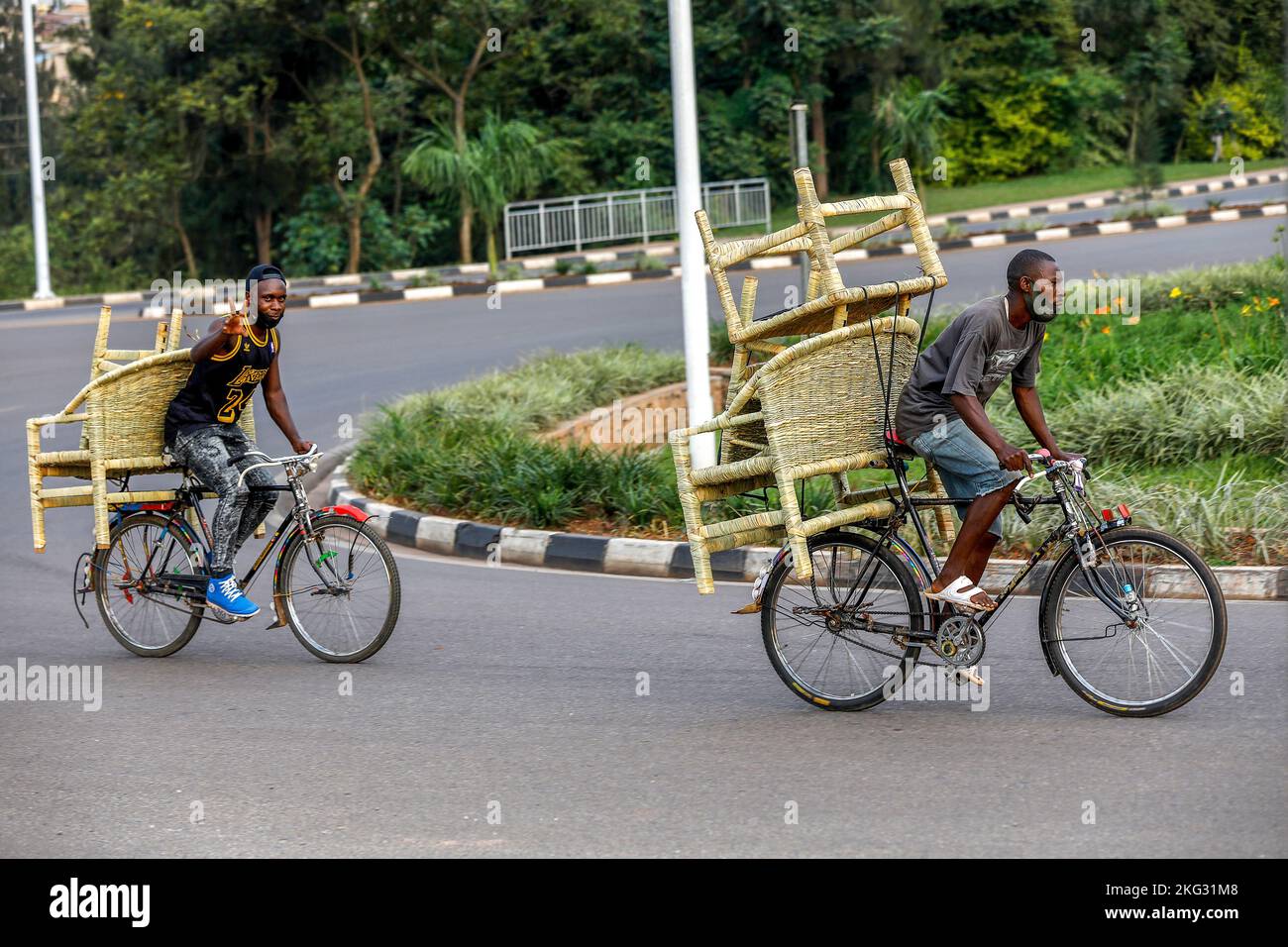 Men riding bikes loaded with furniture in Kigali, Rwanda Stock Photo