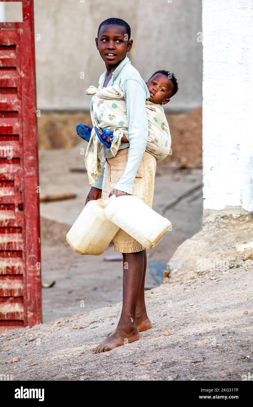 Siblings Rwanda Girl carrying her sibling and fetching water in Kigali, Rwanda Stock ...