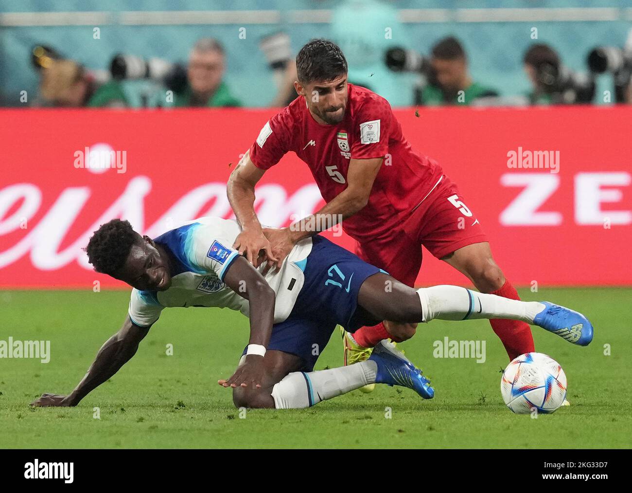 England's Bukayo Saka (left) and Iran's Milad Mohammadi battle for the ball during the FIFA World Cup Group B match at the Khalifa International Stadium in Doha, Qatar. Picture date: Monday November 21, 2022. Stock Photo