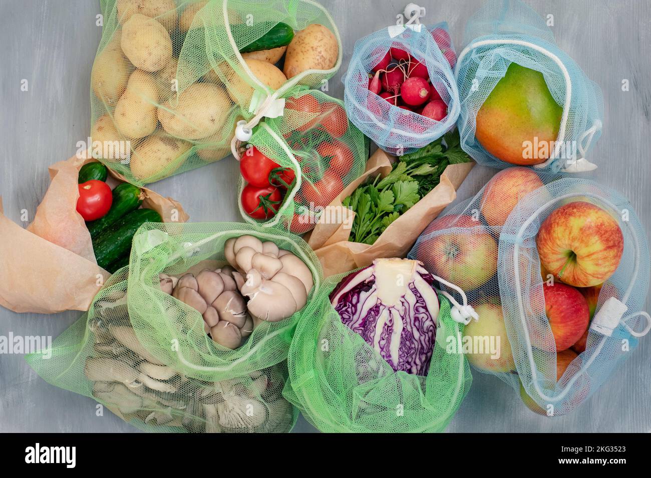 Fruit and vegetables food in reusable net bags on grey wooden background, top view. Zero waste and eco friendly concept Stock Photo