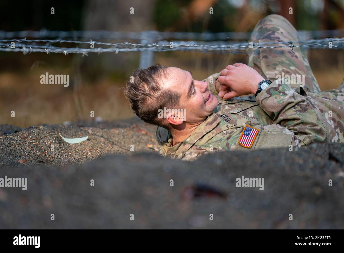 Staff Sgt. Keith Estes from Medical Department Activity, Camp Humphreys, South Korea, crawls under the Low Wire during the Obstacle Course Test in the 2022 Medical Readiness Command, Pacific Best Medic Competition Wednesday, October 26th 2022 at Joint Base Lewis-McChord. Stock Photo