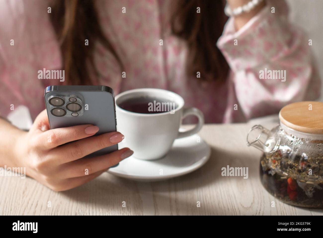 woman drink tea searching for information in phone Stock Photo