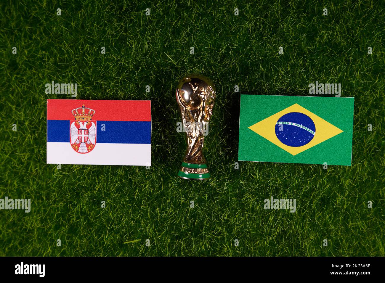 November 20, 2022, Doha, Qatar. Flags of Serbia and Brazil and the FIFA World Cup trophy on the green lawn of the stadium. Stock Photo