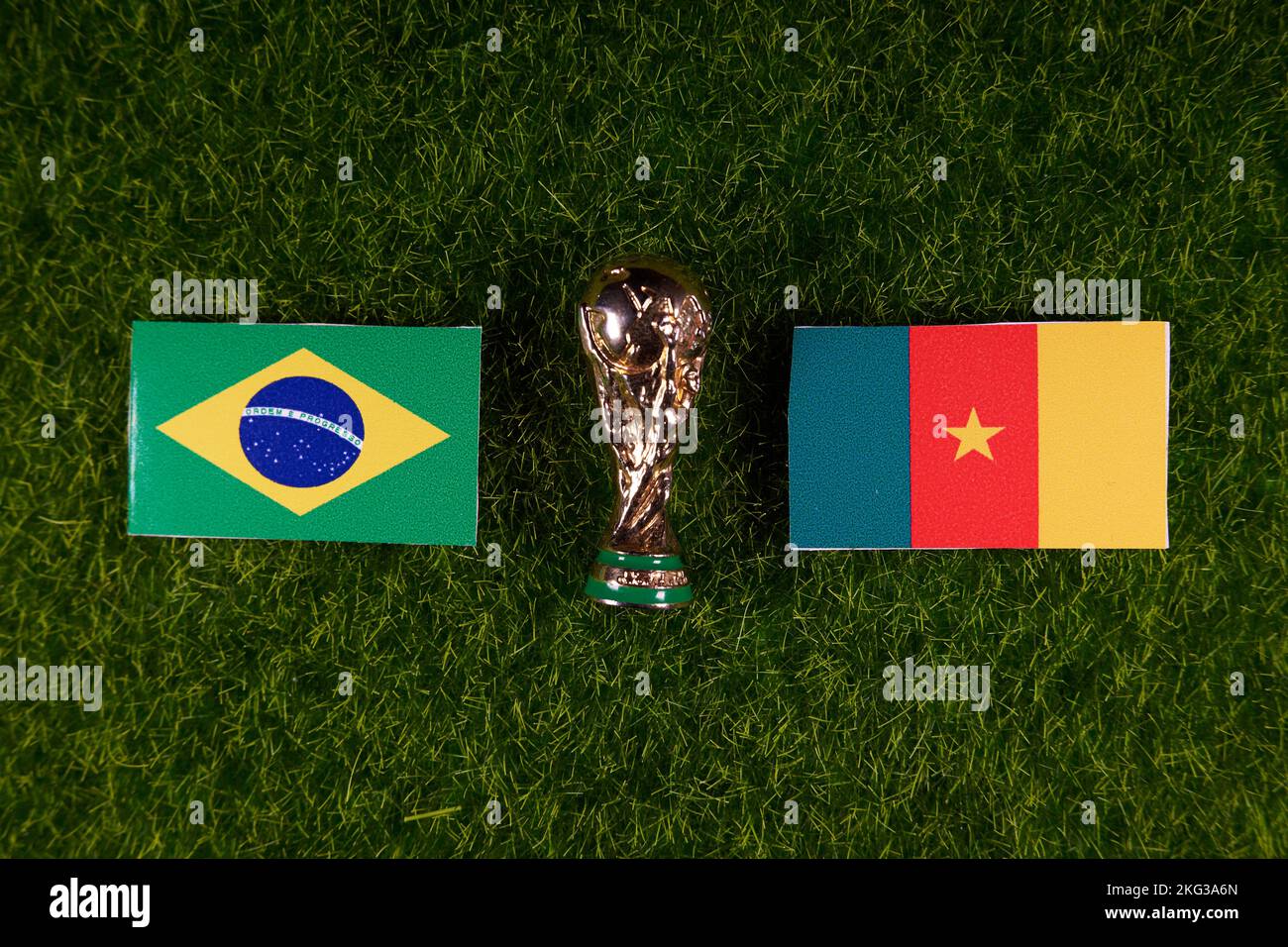 November 20, 2022, Doha, Qatar. Flags of Brazil and Cameroon and the FIFA World Cup trophy on the green lawn of the stadium. Stock Photo