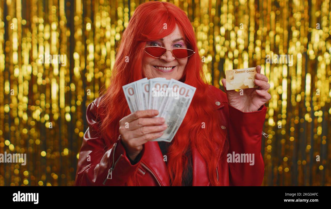 Senior tourist woman showing plastic credit bank card advertising transferring money cashless, purchases online shopping sale discount internet order delivery purchase. Grandmother on shiny background Stock Photo
