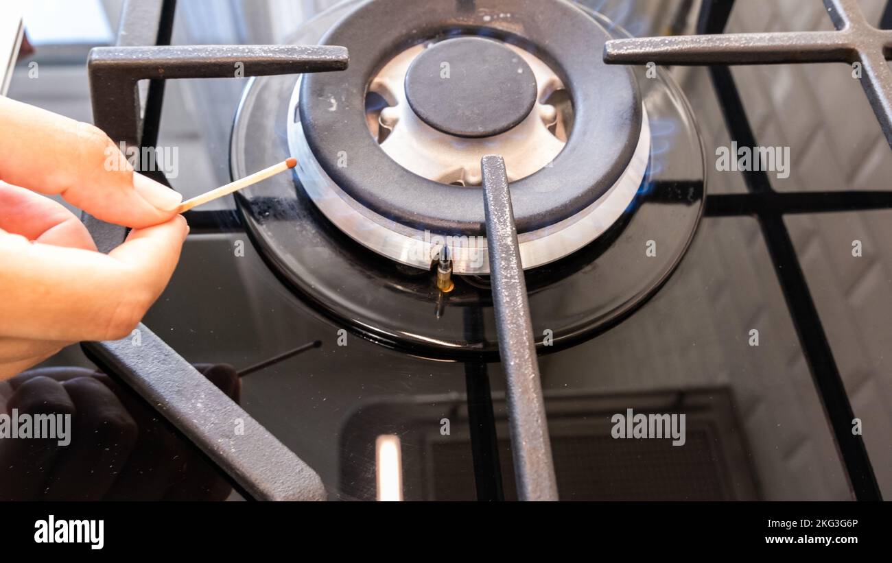 Hand turns on the gas burner on the gas stove Stock Photo Alamy