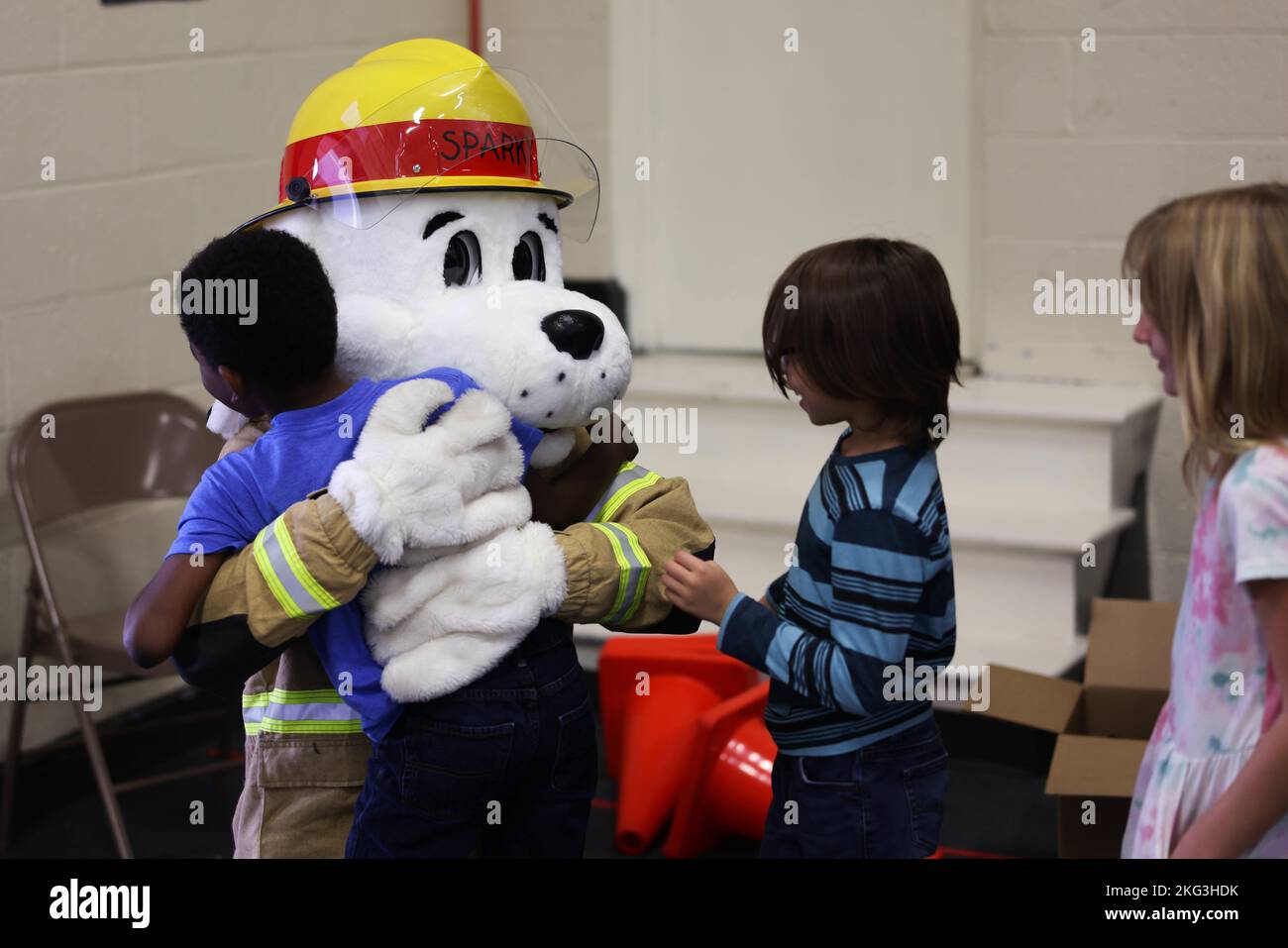 Josh Young, a firefighter with the Cherry Point Fire Department, dresses up as Sparky the Fire Dog and hugs students after a fire safety class at Graham A. Barden Elementary School, Havelock, North Carolina, Oct. 28, 2022. Members of the Cherry Point Fire Department taught the young students about fire safety and displayed the various tools and equipment firefighters use while fighting fires. Stock Photo