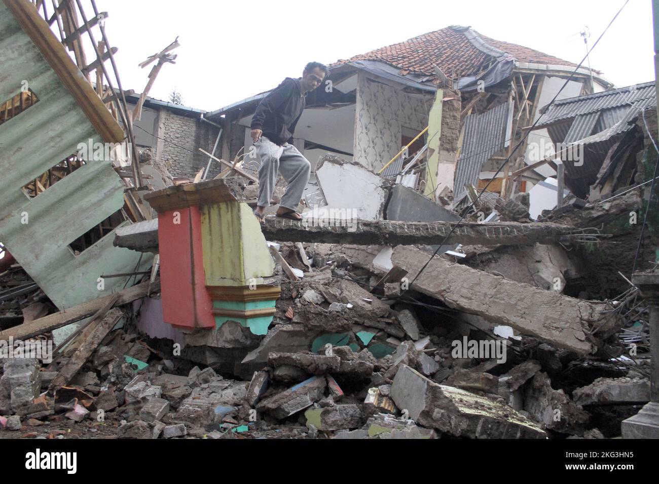 West Java, Indonesia. 21st Nov, 2022. A man walks on the debris of damaged houses after a 5.6-magnitude earthquake in Cianjur, West Java, Indonesia, Nov. 21, 2022. At least 62 people were killed, 25 went missing and about 700 others were injured after a 5.6-magnitude earthquake hit Indonesia's West Java province on Monday, officials said. Credit: Sandika Fadilah/Xinhua/Alamy Live News Stock Photo