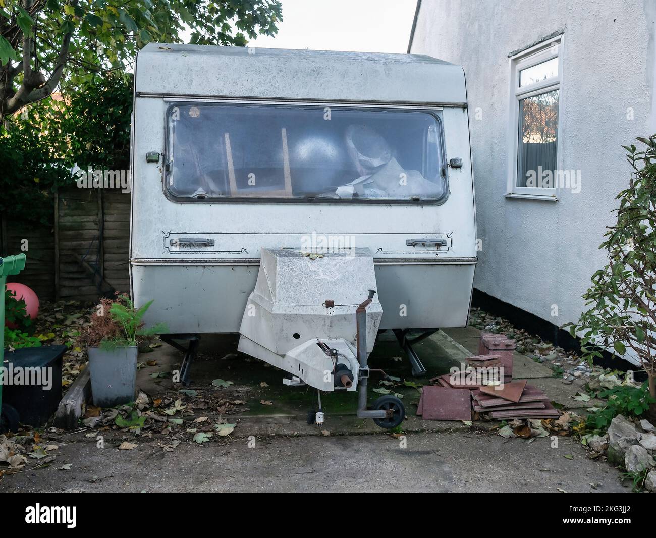 Weather worn Caravan parked in front garden full of furniture Stock