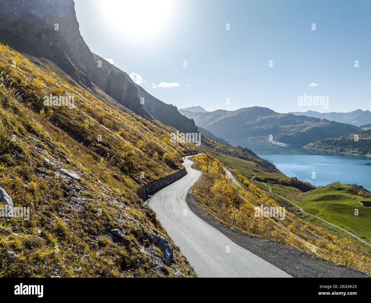 Aerial view of pathway side lake surrounded by rocky grassland slopes