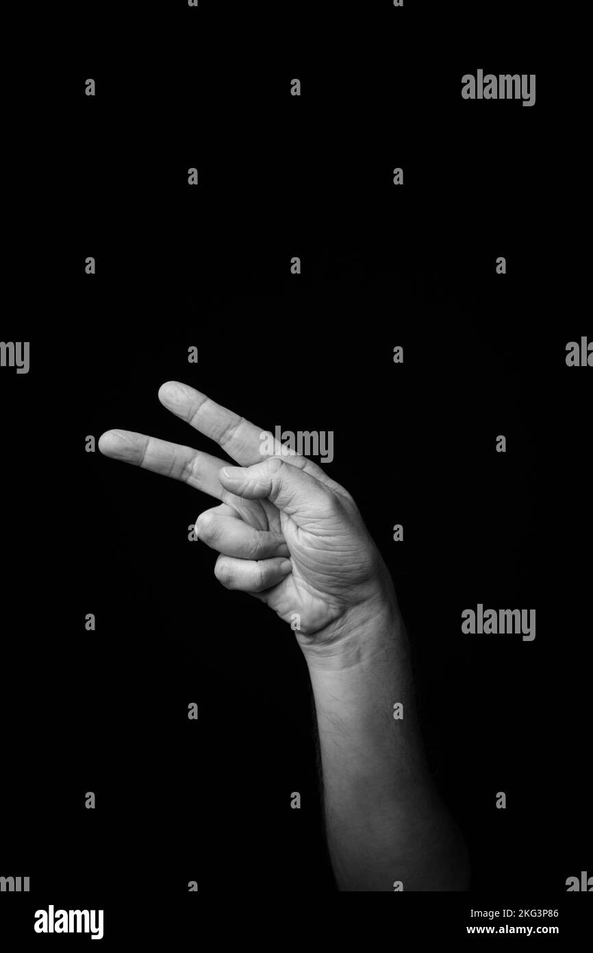 Dramatic black and white image of a male hand fingerspelling the Fench