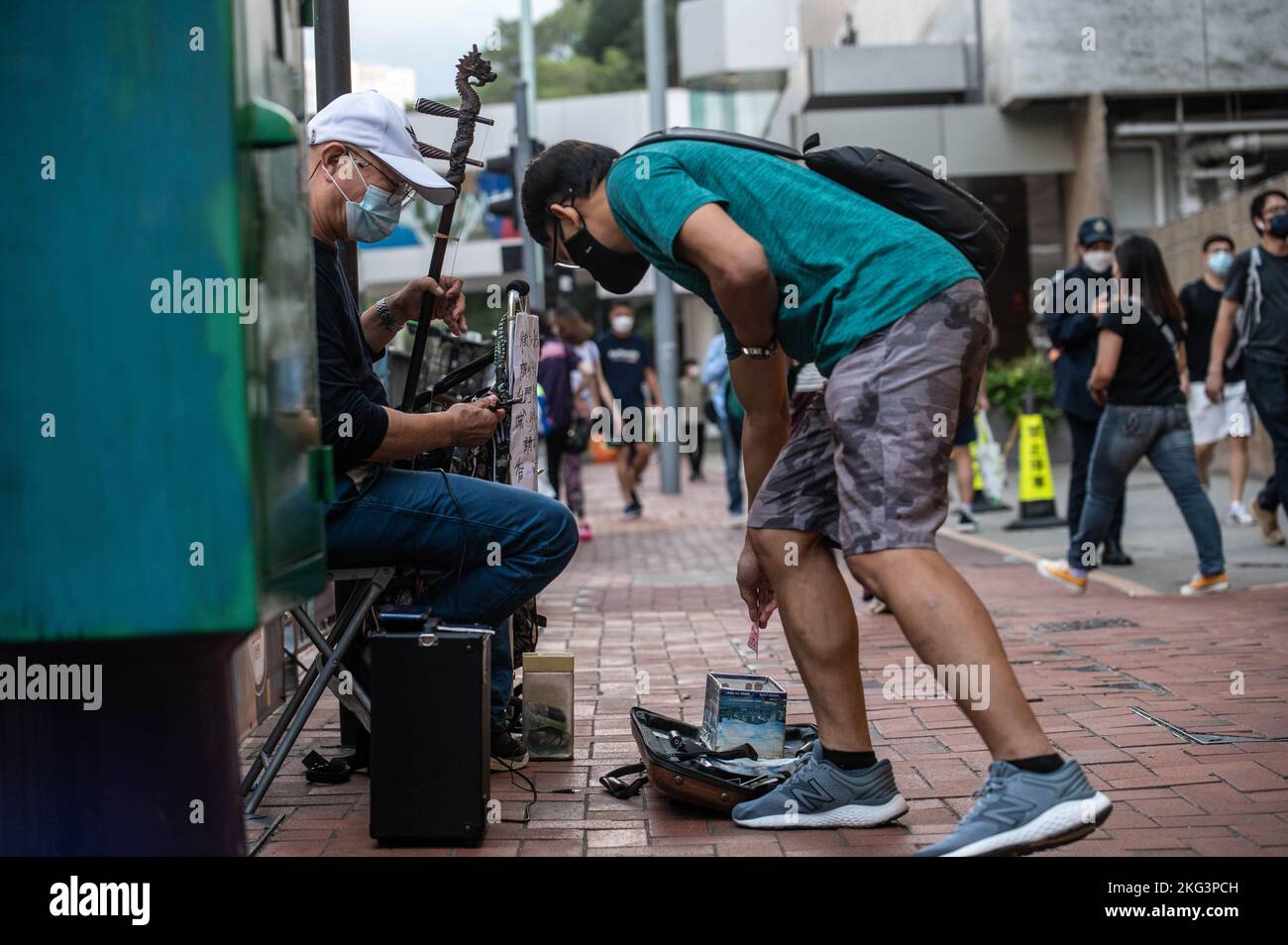 Hong Kong, China. 19th Nov, 2022. A man offers money to a musician playing 'Glory to Hong Kong' and 'Do You Here The People Sing?' on an erhu in front of Quarry Bay Station in Hong Kong. 'Glory to Hong Kong', considered an unofficial anthem of the 2019 pro-democracy protests, has made headlines lately due to it being mistaken for the actual Chinese national anthem at multiple international rugby events. In Hong Kong, questions persist as to the legality of playing or performing this song in public under the National Security Law. Credit: SOPA Images Limited/Alamy Live News Stock Photo
