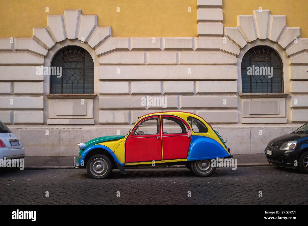Colorful and quirky customized Volkswagen Beetle parked on the side of a cobblestone street in Rome, Italy. Classic car in a catchy color block. Stock Photo