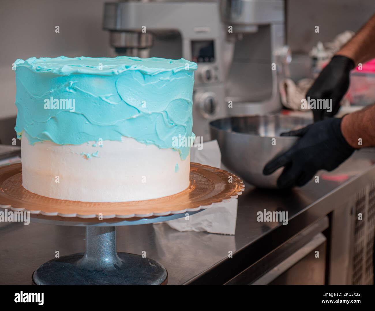 cake designer smoothing a frosted blank cake with turquoise light blue