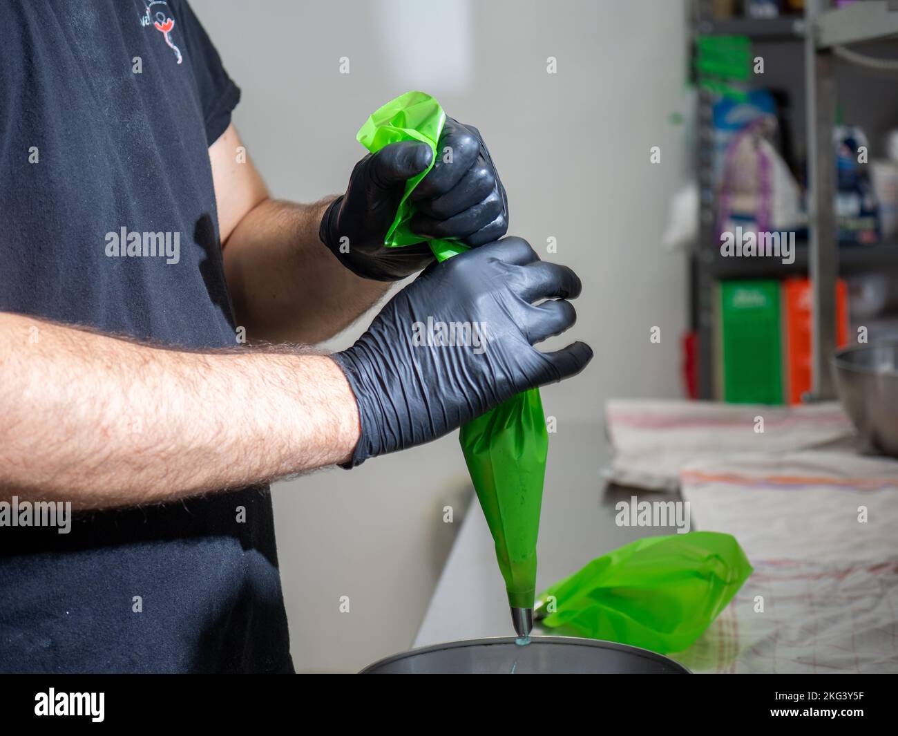 chef using using piping bag pink butter cream filling to decorate frosted icing cake Stock Photo