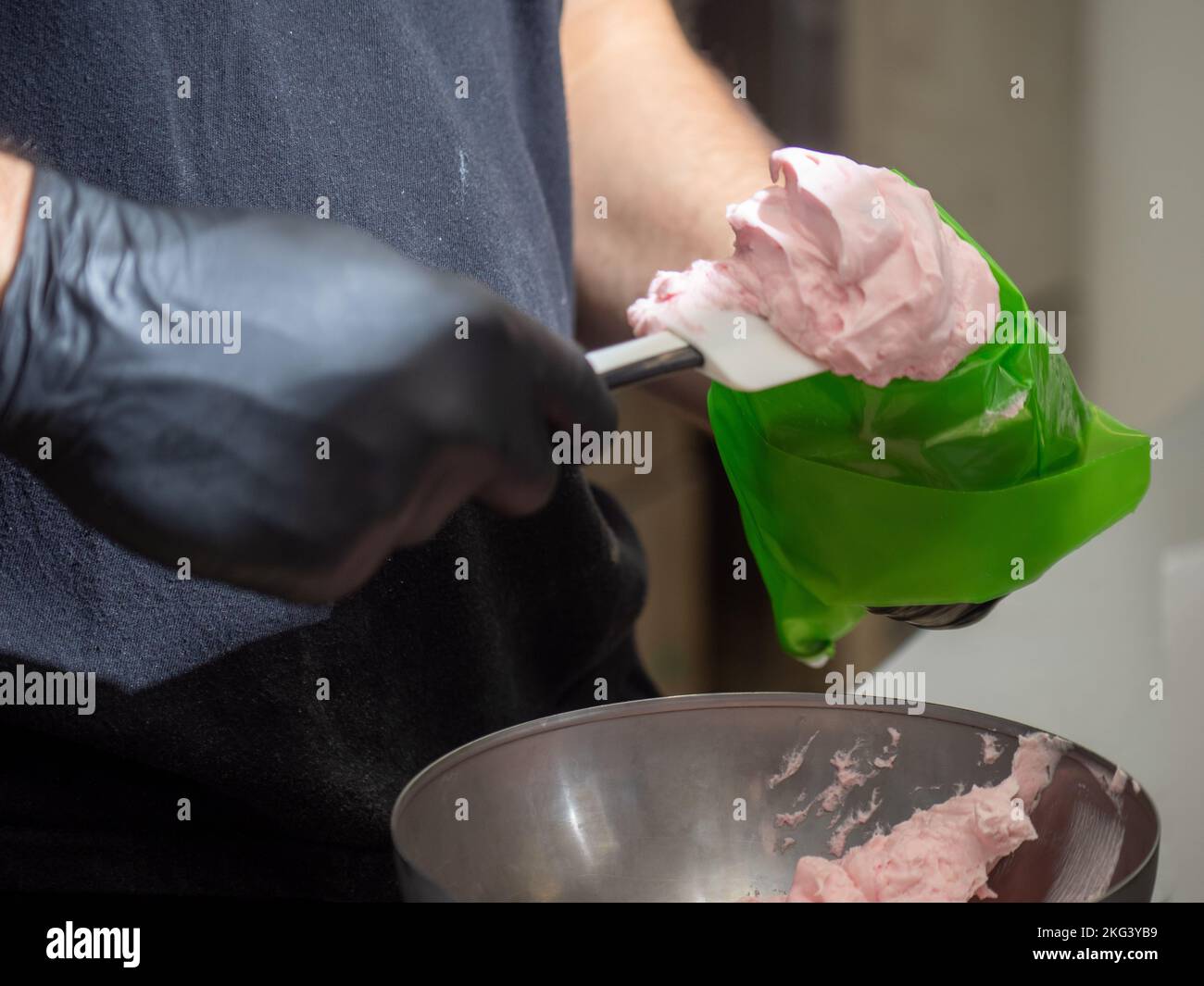 chef using using piping bag pink butter cream filling to decorate frosted icing cake Stock Photo