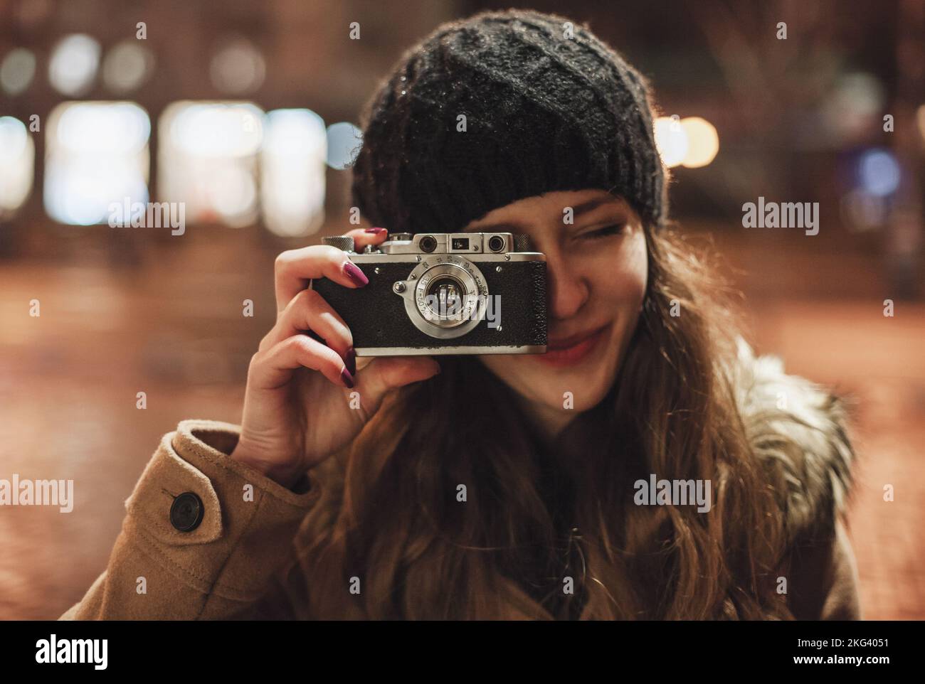 Hipster girl with retro camera taking photos in the night city street Stock Photo