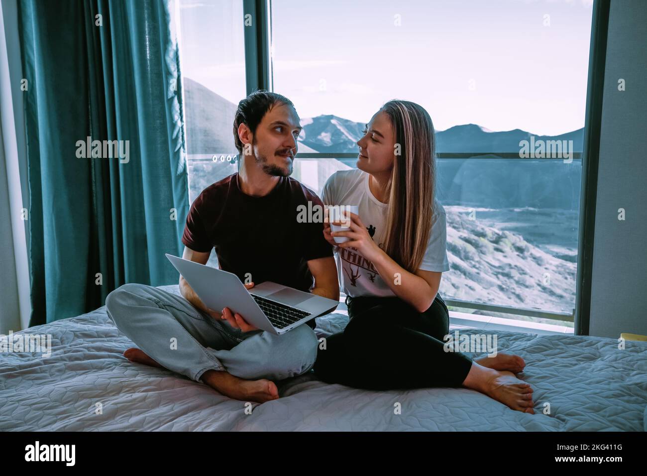 Couple at home sitting on the bad with laptop Stock Photo