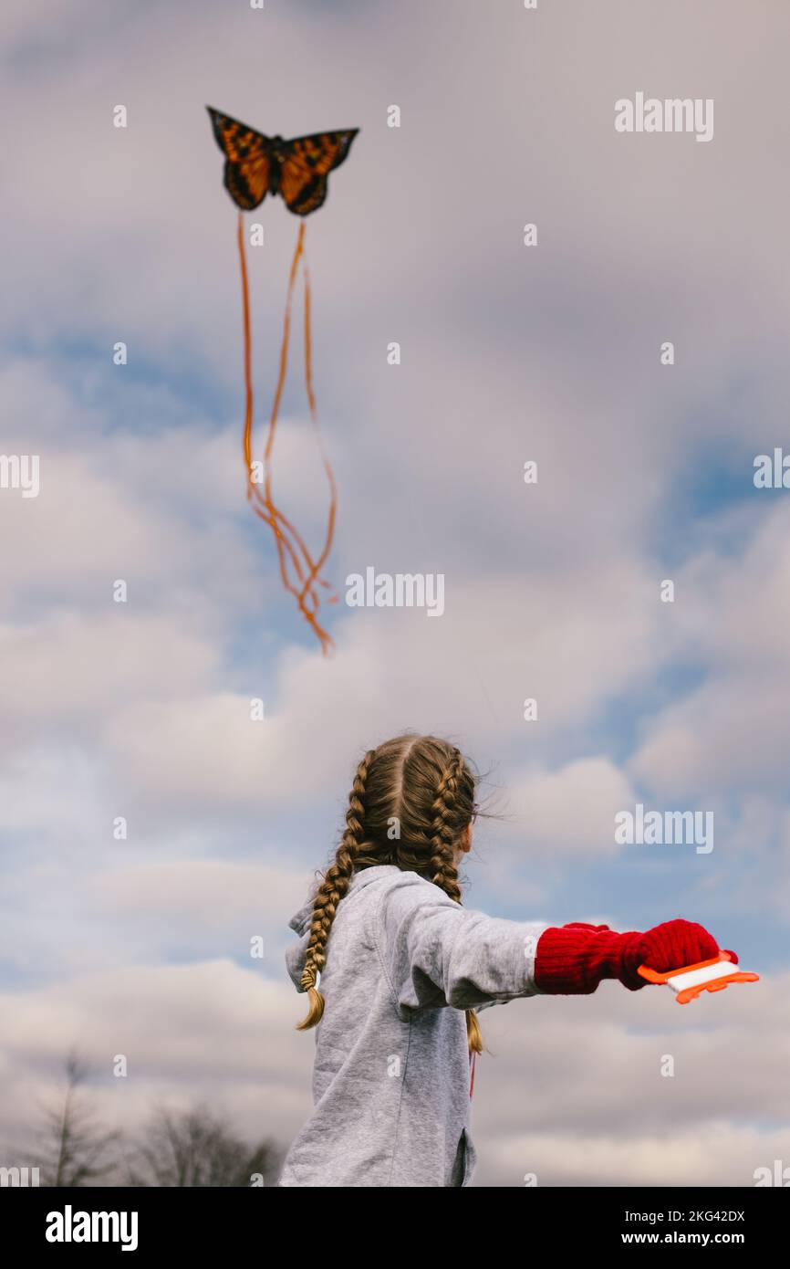 Girl flies butterfly kite in the blue sky with white clouds in spring Stock Photo