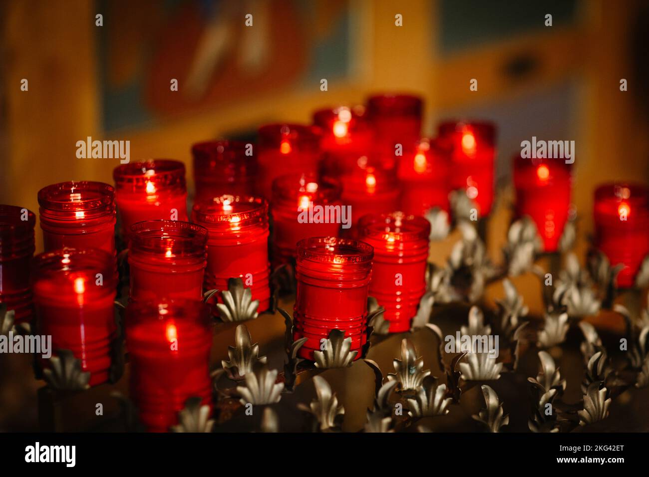 About twenty glowing red prayer candles in gold candle holders Stock
