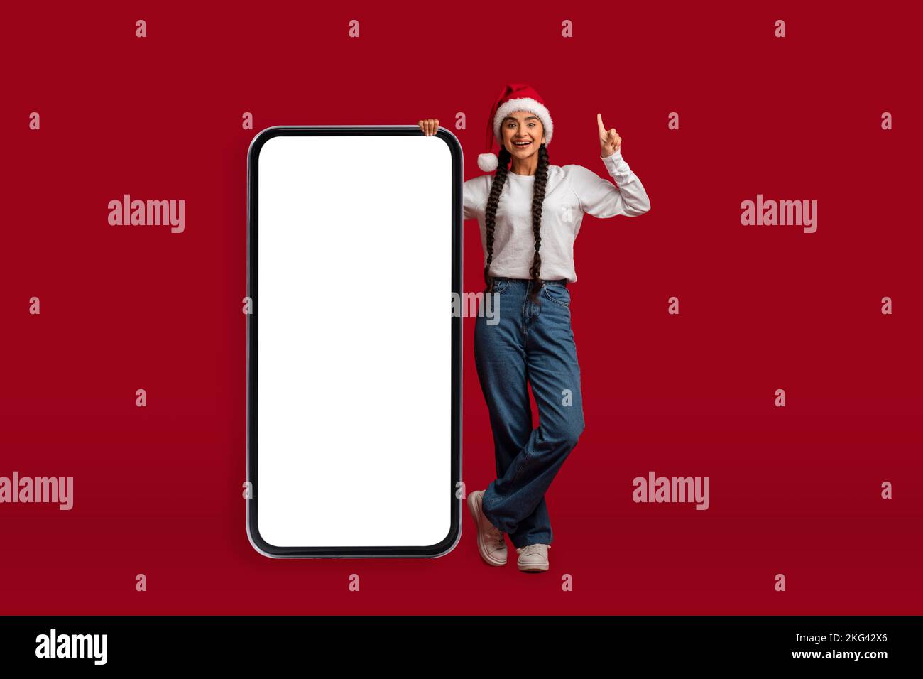 Chistmas Idea. Excited Arab Woman In Santa Hat Standing Near Blank Smartphone Stock Photo