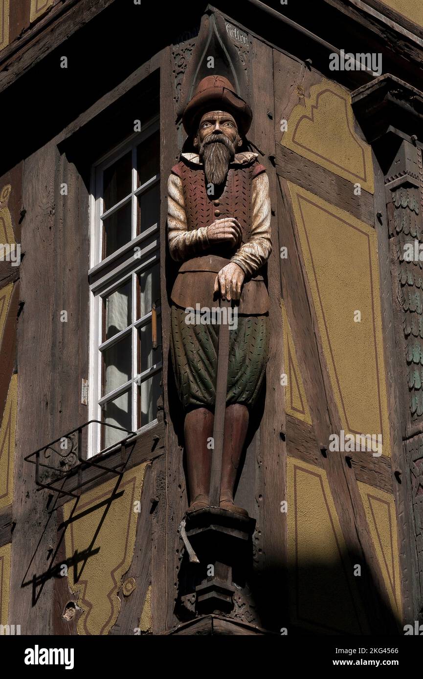 Le Drapier, a sculpted wooden early-1600s draper or cloth merchant.  On the corner post of the timber-framed Maison zum Kragen (House of the Collar) at 9 Rue des Marchands in the historic heart of Colmar, Alsace, Grand Est, France.  The house was built in 1419, but was rebuilt in 1588 after it collapsed. Stock Photo