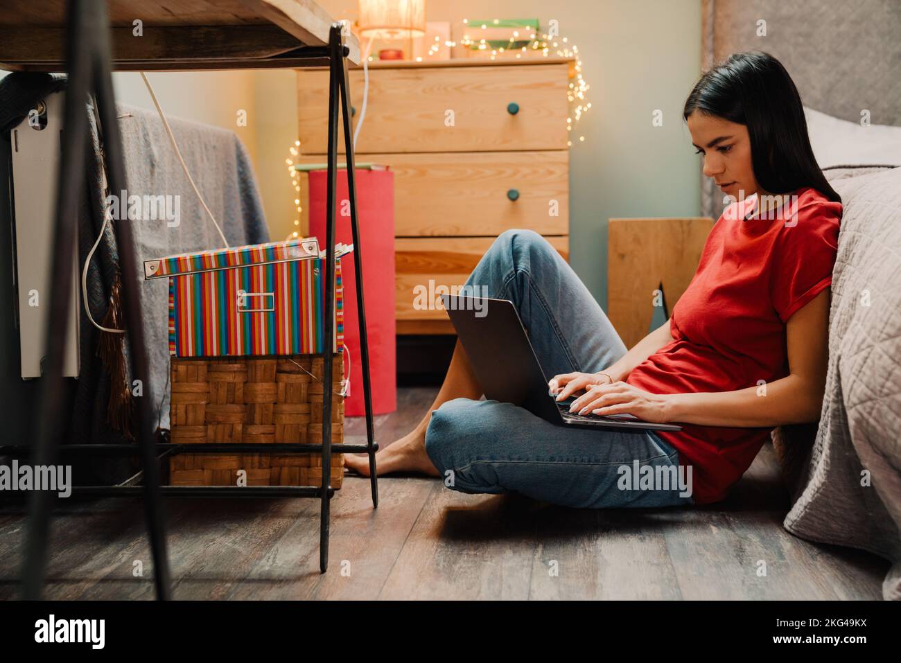 Young hispanic woman working with laptop while sitting on floor at home ...
