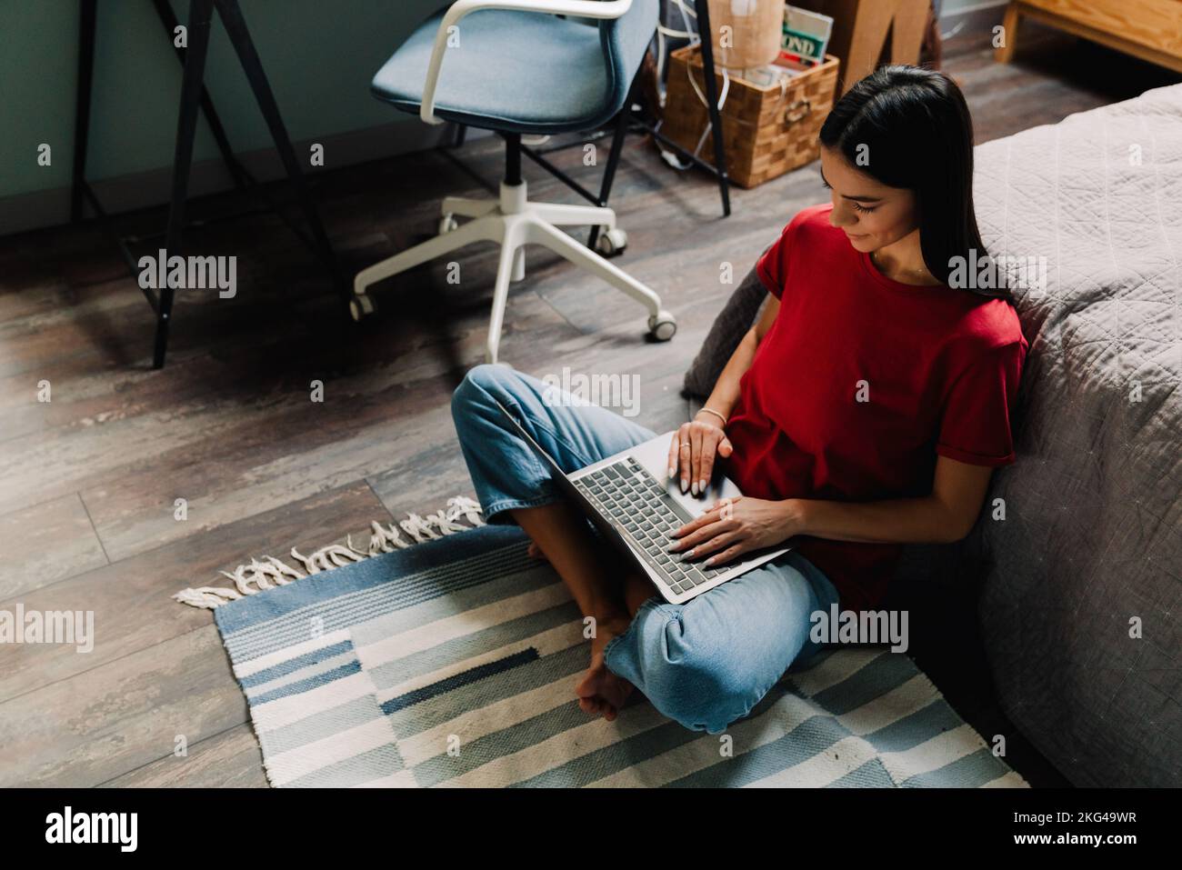 Young hispanic woman working with laptop while sitting on floor at home ...