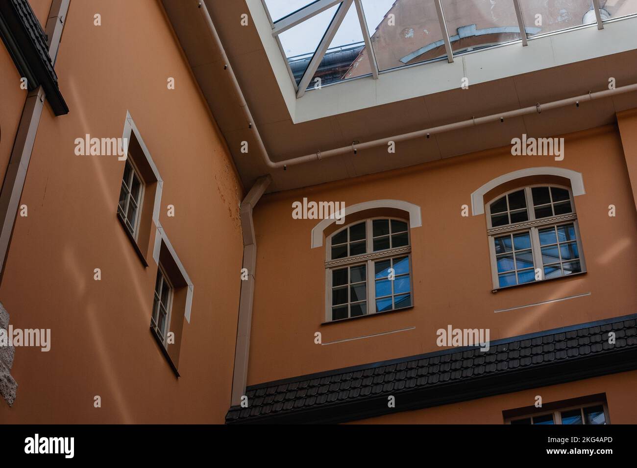 Orange wall of residential house with wooden windows and panes and rainwater drain pipes and glass roof. Stock Photo