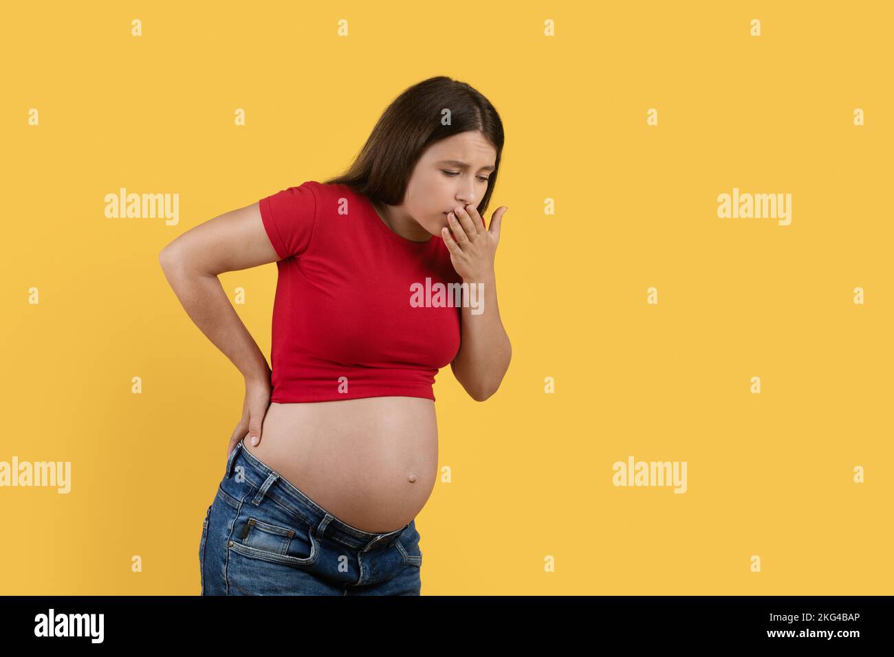 Morning Sickness. Pregnant Woman Suffering Nausea While Standing Over Yellow Studio Background Stock Photo