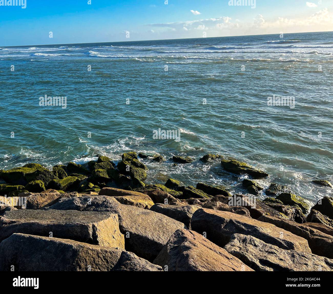 A scenic view of the sea waves hitting the rocks on a sunny day Stock ...
