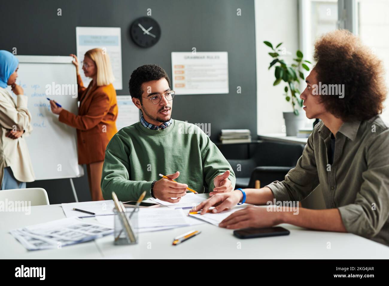 Young confident Middle Eastern male student talking to other learner at ...