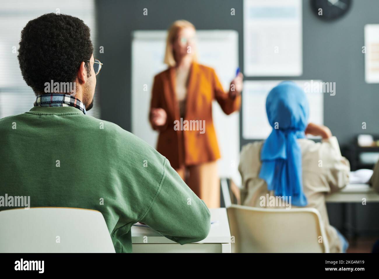 Selective focus on rear view of young Middle Eastern highschool male student sitting by desk at lesson of foreign language Stock Photo