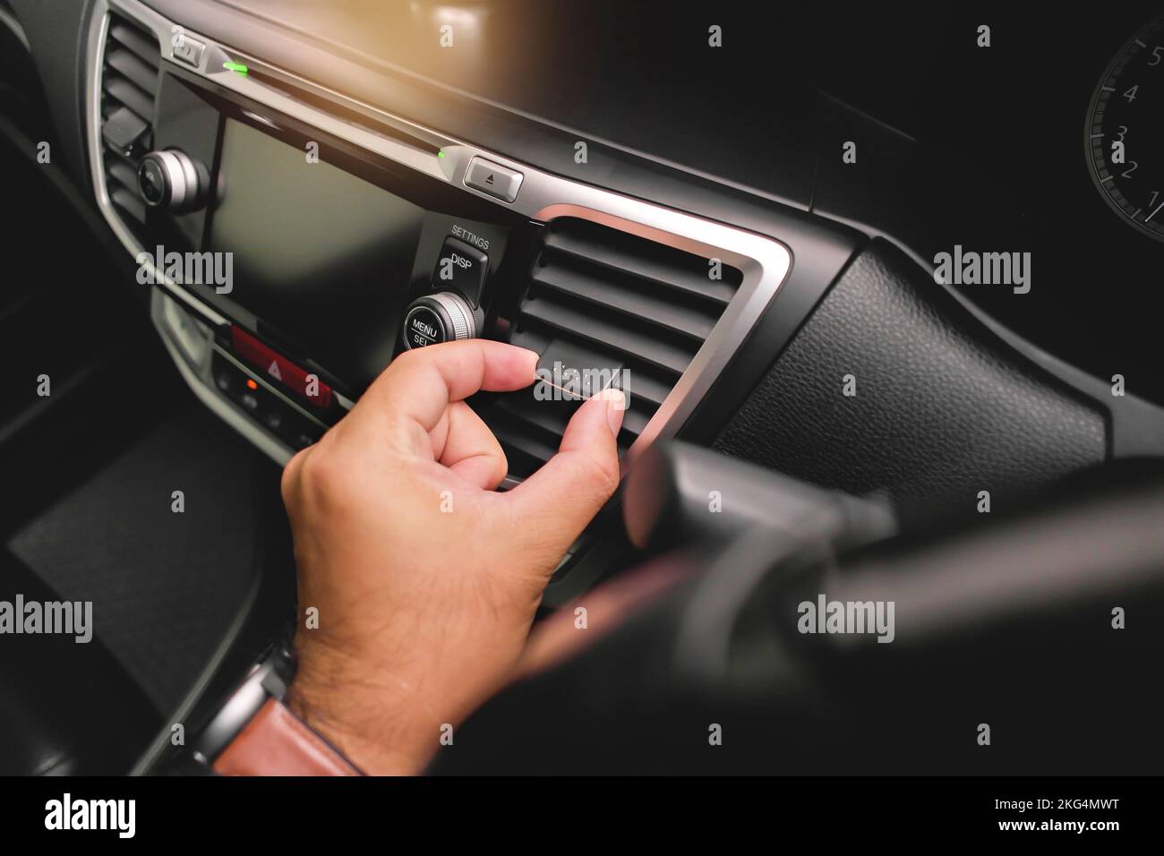 The driver hand adjusts the wind direction of the car air vent in the