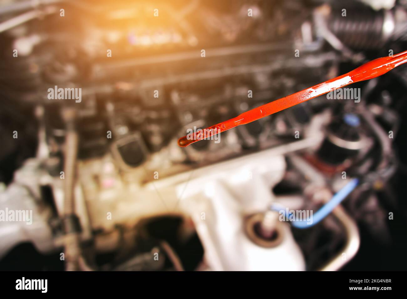 Deteriorating car oil on dipstick with background of blurred engine